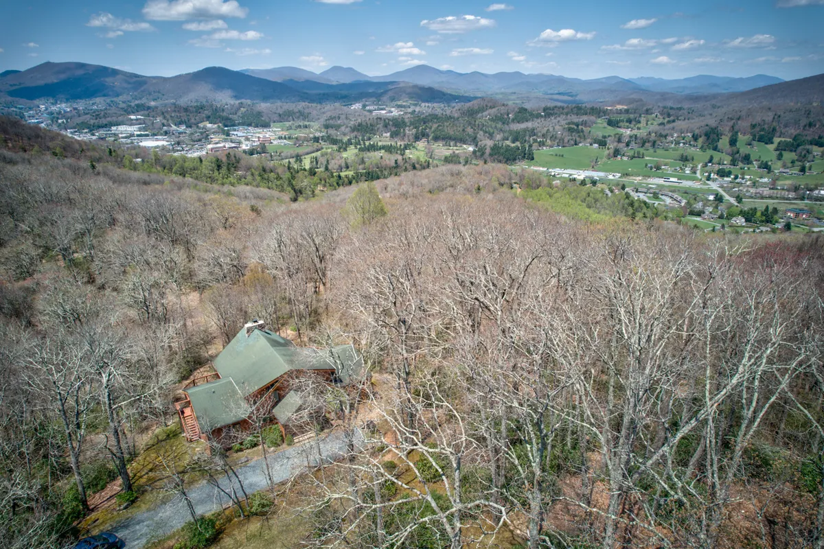 This scenic view captures a majestic mountain range and sprawling valley with a log cabin home in the foreground. The broad, natural landscape emphasizes the property’s mountain setting and the endless opportunities for hiking, walks, and exploration with pets.