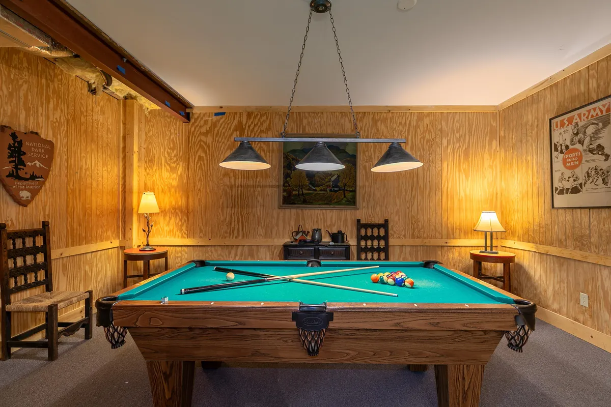 Inside, this recreation/game area features a pool table, welcoming seating, and vibrant wall art under warm lighting. The space is clearly designed for fun family activities, socializing, and relaxation after a day outdoors.